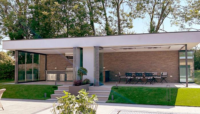 Frameless slide and stack doors fully retracted across a modern rear extension, opening the living space onto a landscaped garden