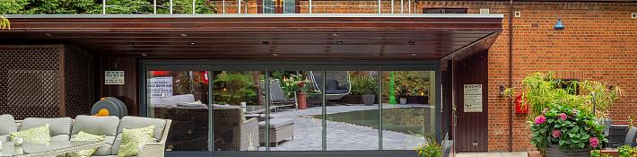 Large frameless picture windows in a country cottage looking out over a tranquil garden pond