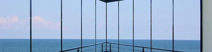 Floor-to-ceiling frameless glass balcony balustrade on a coastal home with uninterrupted sea views