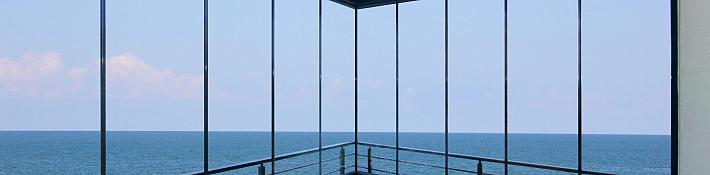 Floor-to-ceiling frameless glass balcony balustrade on a coastal home with uninterrupted sea views