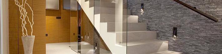 Frameless glass balustrades running alongside a timber staircase in a contemporary home interior