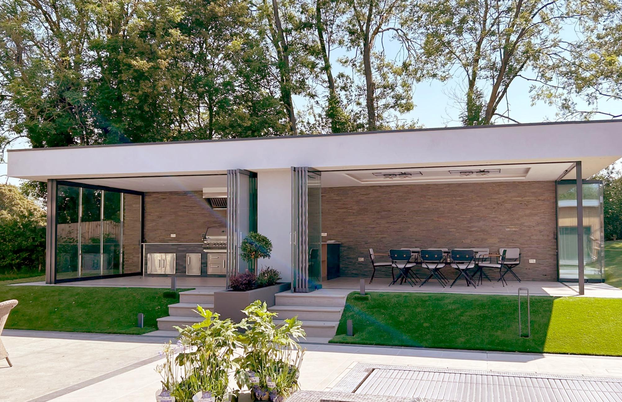 Frameless slide and stack doors fully retracted across a modern rear extension, opening the living space onto a landscaped garden