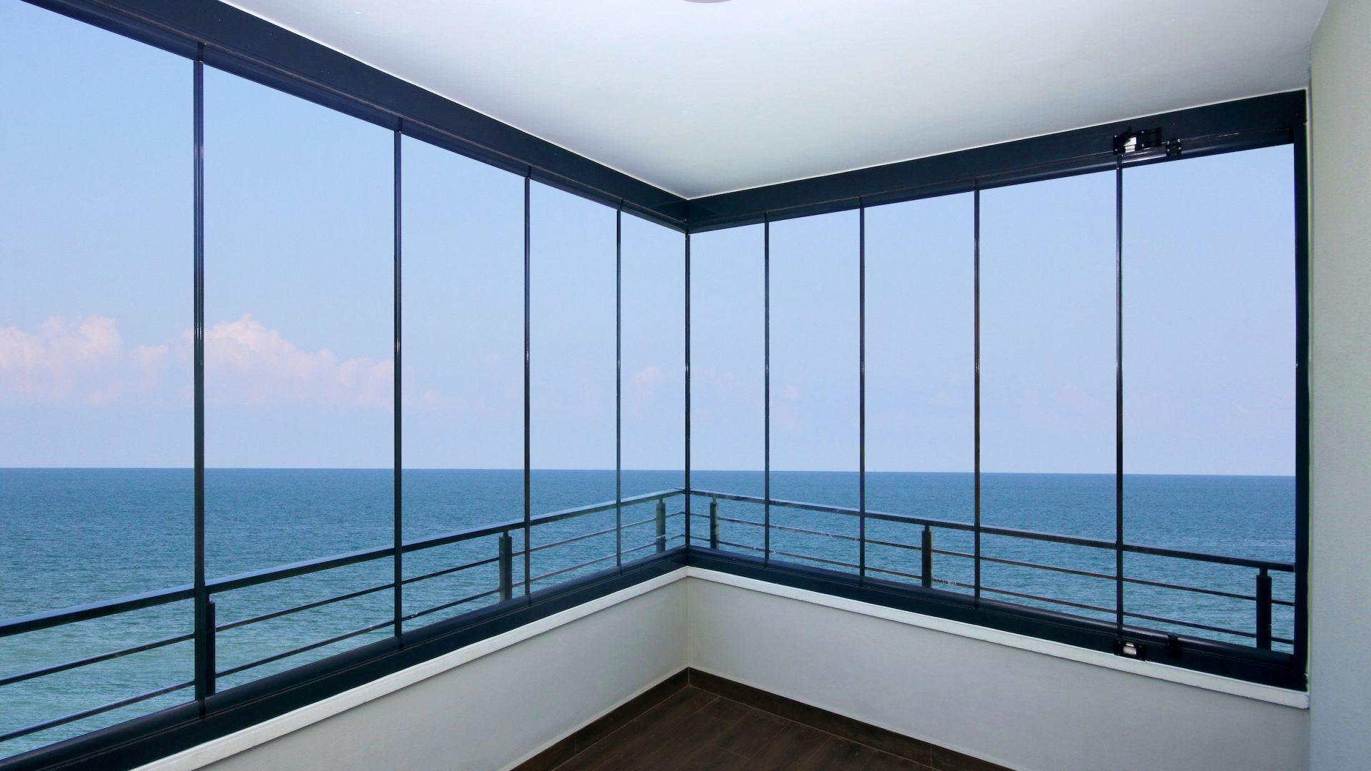 Floor-to-ceiling frameless glass balcony balustrade on a coastal home with uninterrupted sea views