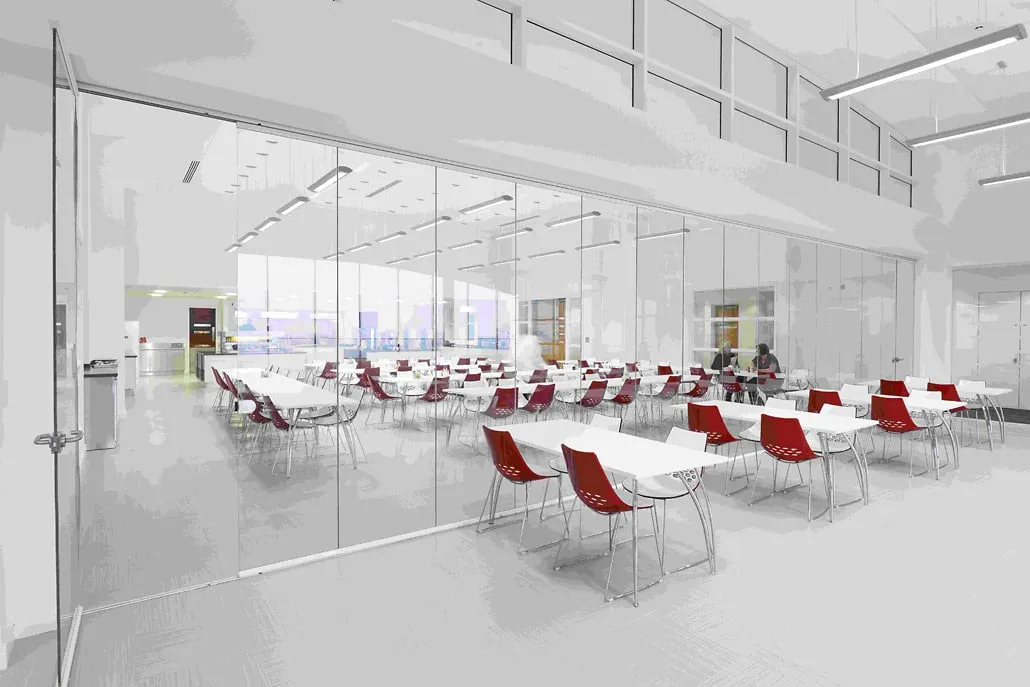 Full-height frameless interior glass doors partitioning a bright office meeting room